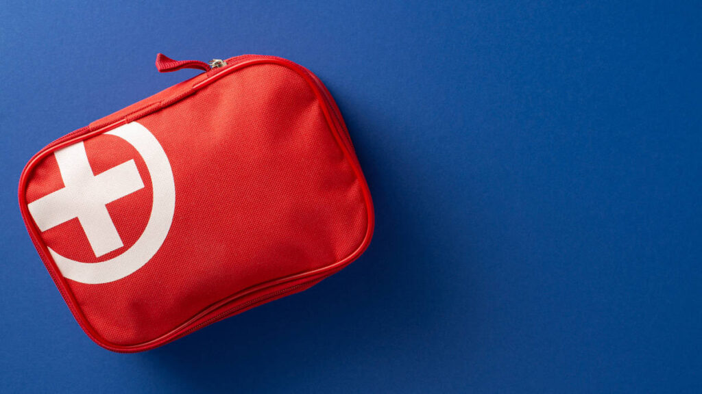 Rotes Erste-Hilfe-Set auf blauem Untergrund.