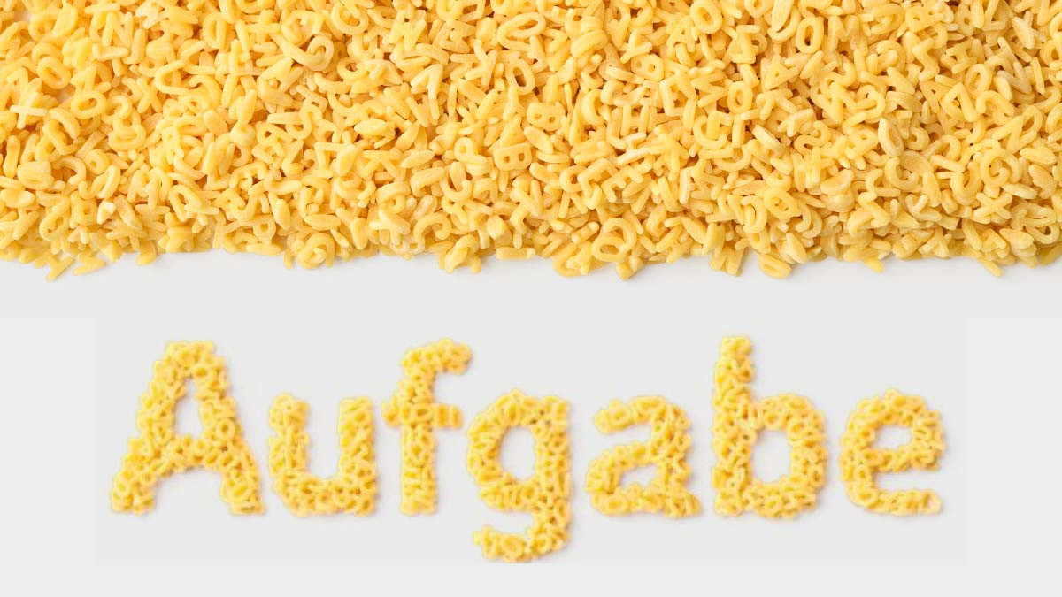 Buchstaben-Nudeln auf weißem Hintergrund mit dem Schriftzug "Aufgabe" aus Nudeln gelegt.