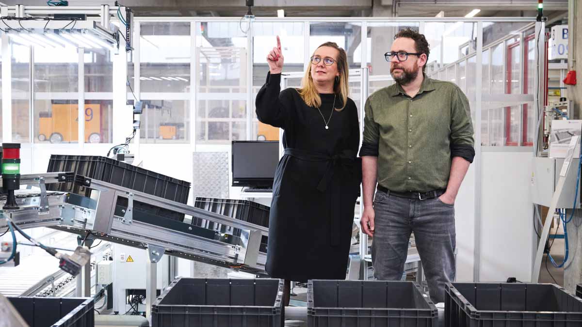 Zwei Menschen stehen in einer Produktionshalle.