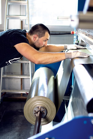 Ein ­Ortlieb-Mitarbeiter bei der Arbeit mit dem Rohmaterial, aus dem später die Taschen gefertigt werden. In der Produktion wird noch viel von Hand gemacht, der ­Automatisierungsgrad ist eher gering.