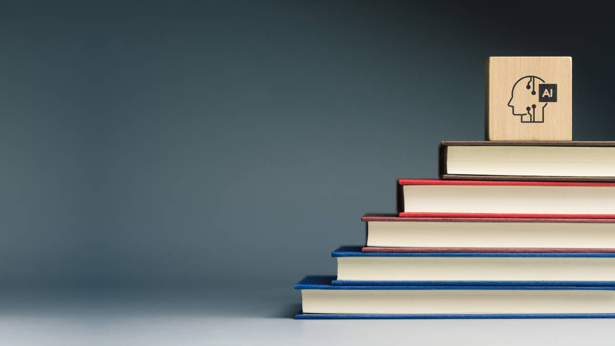 Übereinander gestapelte liegende Bücher, auf denen ein Würfen, mit einem KI-Symbol liegt