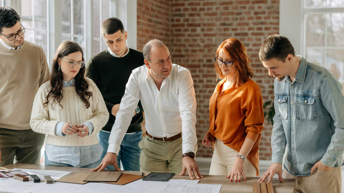 Mehrere Personen stehen in einem Büro um einen Tisch herum